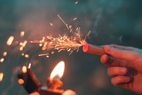 Jongeman verlicht vuurwerk in zijn hand — Stockfoto