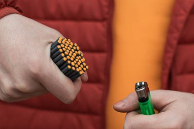 Kırmızı ceketli adam bir sürü küçük fişek yakıyor.