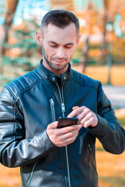 Autumn Park 'ta akıllı telefon kullanan yakışıklı adam.