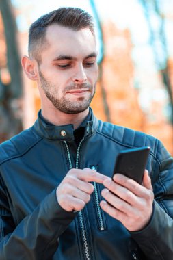 Autumn Park 'ta akıllı telefon kullanan yakışıklı adam.
