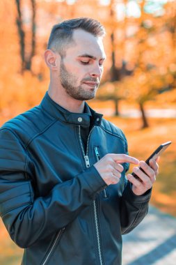 Autumn Park 'ta akıllı telefon kullanan yakışıklı adam.