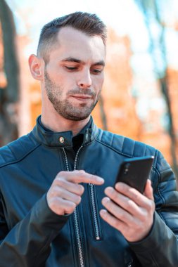 Autumn Park 'ta akıllı telefon kullanan yakışıklı adam.
