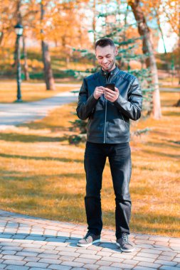 Autumn Park 'ta akıllı telefon kullanan yakışıklı adam.
