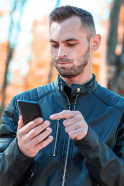 Autumn Park 'ta akıllı telefon kullanan yakışıklı adam.