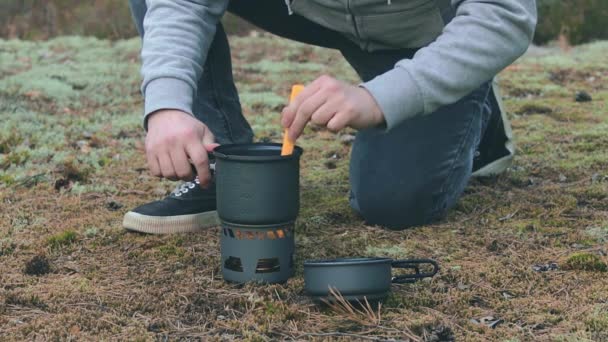 Vandrare kokar pasta med konserverad gryta i en skog — Stockvideo