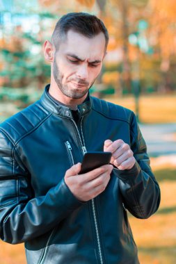 Autumn Park 'ta akıllı telefon kullanan yakışıklı adam.