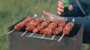 Barbekü yapan adam dışarıda et yiyor.