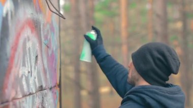 Grafiti çizen genç adam sprey boya kutusu kullanıyor.