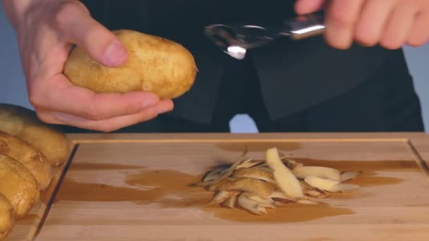 El hombre está pelando patatas en una cocina — Vídeos de Stock