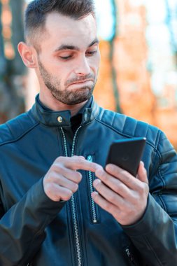 Autumn Park 'ta akıllı telefon kullanan yakışıklı adam.