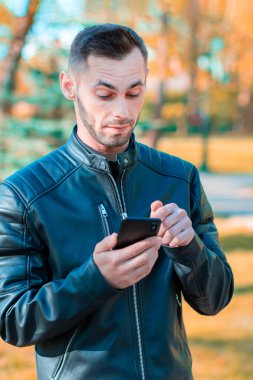 Autumn Park 'ta akıllı telefon kullanan yakışıklı adam.