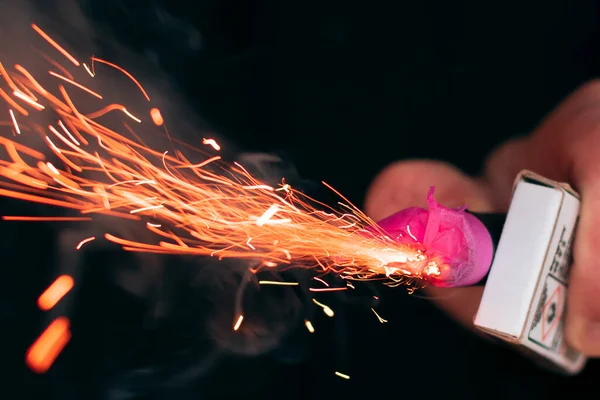 Kıvılcımlar ve dumanla elinde yanan maytap.