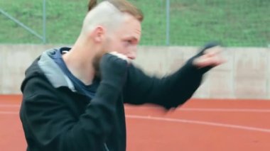 Genç Sakallı Adam dışarıda boks antrenmanı yapıyor.