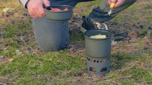 Vandrare kokar pasta med konserverad gryta i en skog — Stockvideo