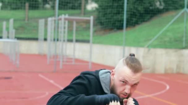 Ung skäggig kille tränar boxning övningar utomhus — Stockvideo