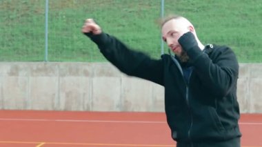 Genç Sakallı Adam dışarıda boks antrenmanı yapıyor.