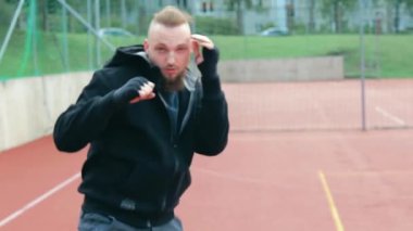 Genç Sakallı Adam dışarıda boks antrenmanı yapıyor.