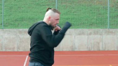 Genç Sakallı Adam dışarıda boks antrenmanı yapıyor.