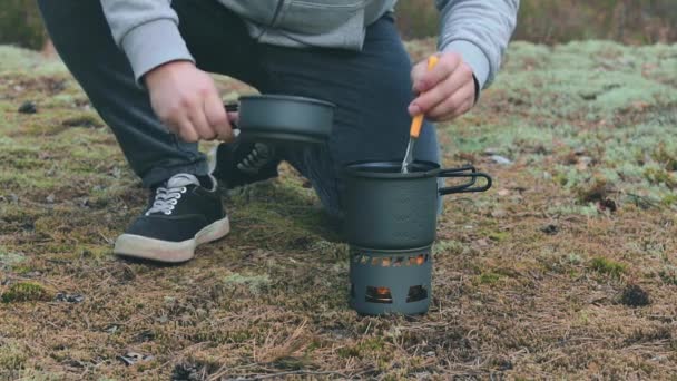 Vandrare kokar pasta med konserverad gryta i en skog — Stockvideo