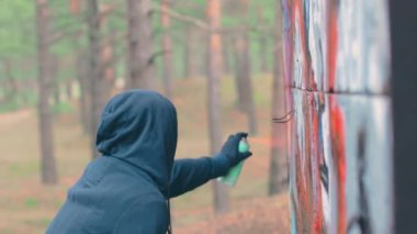 Grafiti çizen genç adam sprey boya kutusu kullanıyor.