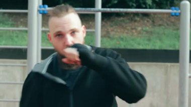 Genç Sakallı Adam dışarıda boks antrenmanı yapıyor.