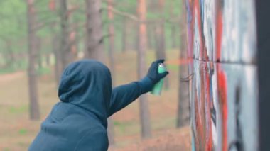 Grafiti çizen genç adam sprey boya kutusu kullanıyor.