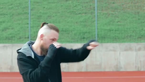 Ung skäggig kille tränar boxning övningar utomhus — Stockvideo