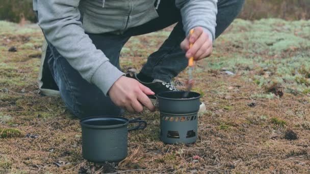 Vandrare kokar pasta med konserverad gryta i en skog — Stockvideo