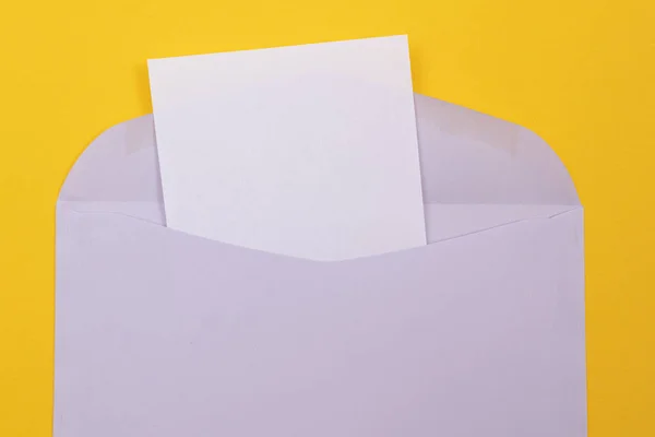 Fialová obálka s prázdným bílým listem papíru uvnitř — Stock fotografie