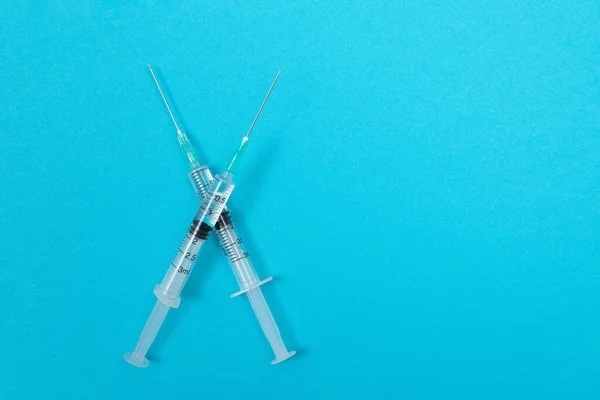 Védőoltás vagy emlékeztető oltás koncepció - Két orvosi fecskendő a kék asztalon — Stock Fotó