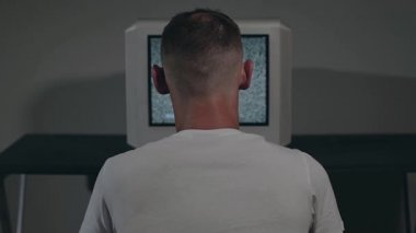 Beyaz tişörtlü Zombi Adam Eski Gümüş TV karşısında oturuyor