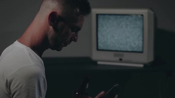 Hombre de camiseta blanca está sentado contra la vieja televisión de plata — Vídeos de Stock