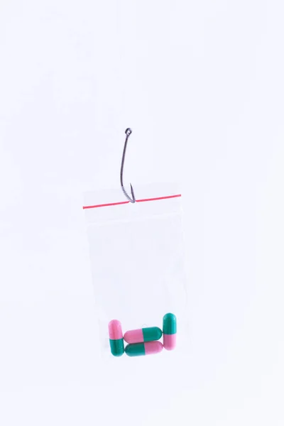 釣針の上に小さなジップロックバッグにぶら下がっている色の丸薬や錠剤 — ストック写真