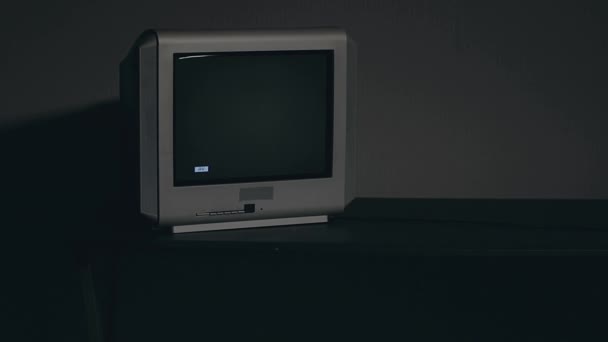 Побите телебачення. Старе срібне телебачення на чорному столі в темній кімнаті — стокове відео