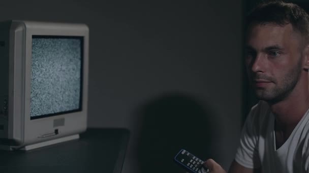 Контроль розуму - Зомбіфікований чоловік у білій футболці перемикає канали на телевізорі — стокове відео