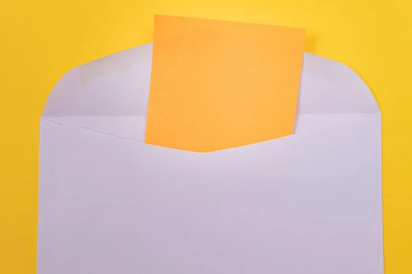 Envelope violeta com folha de papel laranja em branco dentro — Fotografia de Stock