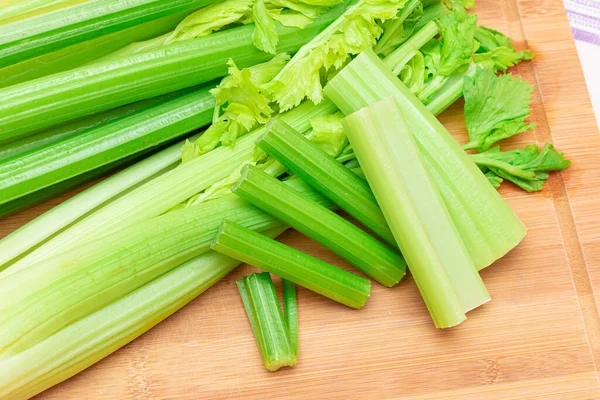 Fresh Celery Stem and Chopped Celery Sticks on Wooden Cutting Board Stock Image