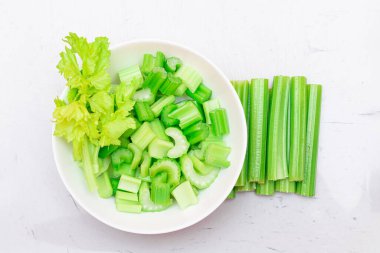 Taze doğranmış kereviz, beyaz kasede su damlalarıyla birlikte çubuklar ve dilimler.