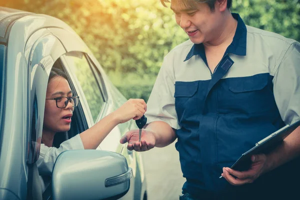 車の整備士は 車の検査の詳細を説明しています 修理前に理解のために所有する女性のために 顧客は機械工に車の鍵を送ります — ストック写真