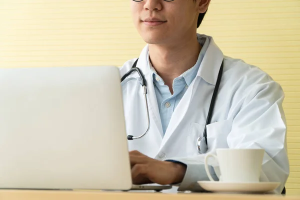 Young Asian doctors giving a consultation to a patient and show medical information and diagnosis on a laptop in office at the hospital. Concept of healthcare and medical service