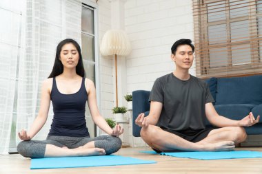 Evde karantina üzerine bir online derste nilüfer minderinde oturmuş yoga egzersizi yapan sağlıklı, genç Asyalı çift. Yeni normal yaşam tarzı için Teknoloji kavramı