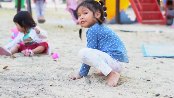 A menina asiática está jogando a areia no playground. Jogar é um desenvolvimento de aprendizagem. E construir músculos para crianças. — Vídeo de Stock