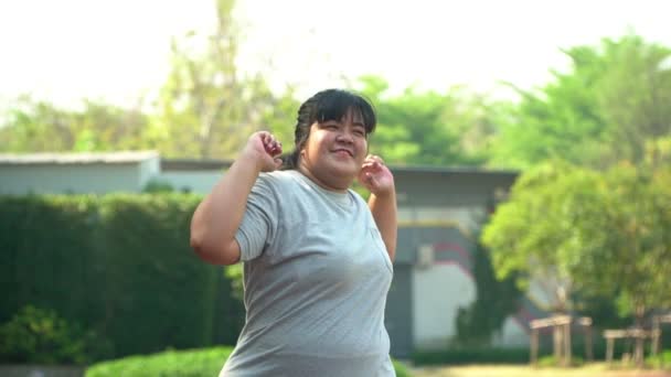 Las mujeres asiáticas con sobrepeso felices se calientan antes de hacer ejercicio en el parque. Concepto de cuidado de la salud y pérdida de peso a través del ejercicio - inyección en cámara lenta. — Vídeos de Stock