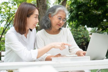 Yaşlı kadınlara ders veren Asyalı kız çocuğu emeklilikten sonra bilgisayar bilgisayarında sosyal medya kullanıyor. Öğrenme teknolojisi ve yaşlıların adaptasyonu kavramı