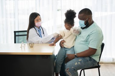 Enjeksiyon için Asyalı doktor şırınga iğnesi, Afrika kökenli Amerikalı çocuklar koronavirüsü ve gribi önlemek için aşılanıyorlar. Aşıdan gelen bağışıklık kavramı