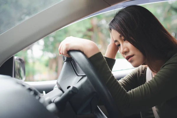 Stressed and unhappy Asian woman driver sitting inside her vehicle and feeling sad and angry. Car accidents are caused by negligence. And the driver tired. Drunk and Sleepy female hangover.