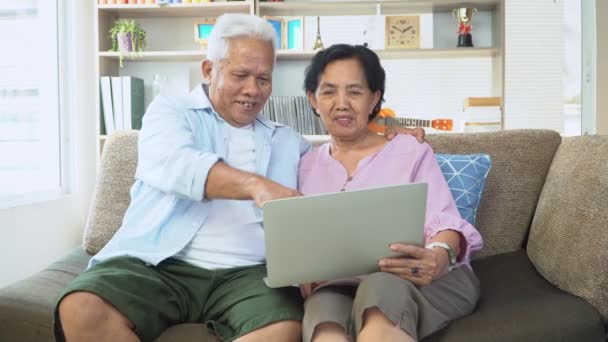 Happy Asian senior couple uses the laptop to find holiday destinations in the holiday season. Koncept šťastného staršího životního stylu po odchodu do důchodu — Stock video