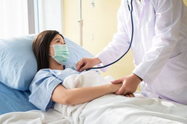 Asyalı kadın doktorlar hastanın elini tutar ve tıbbi tavsiyelerde bulunurken doktorlar da hastanın kalbini kontrol etmek için stetoskop kullanır. Şefkat ve şefkat kavramı