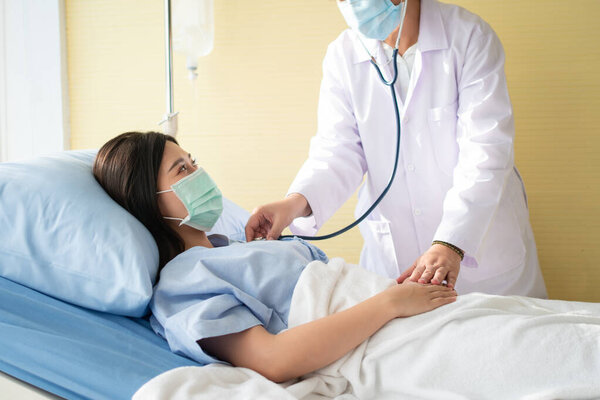 Women Asian doctors hold the patient hand and encourage and provide medical advice While doctors use Stethoscope for checking the patient heart in bed. Concept of Care and compassion