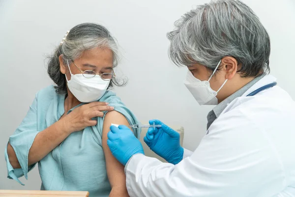 Doctors wear medical masks and vaccinated to senior women patients for the prevention of coronavirus and flu. Concept of immunization from inoculation